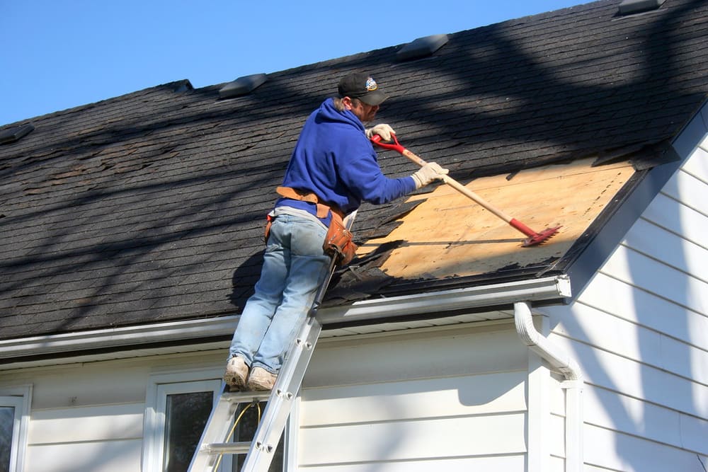 Roofer working from a ladder near a roof edge